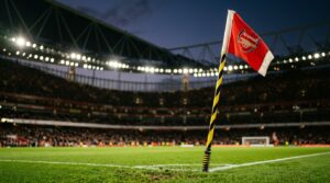A low angle shot of a pristine corner flag at the Emirates Stadium with blurred stadium lights in the background.