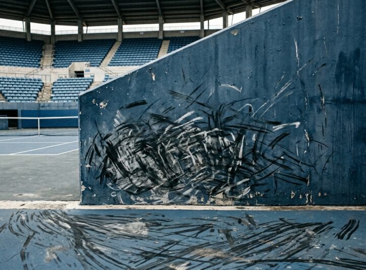Scuff marks from tennis shoes clustered near the back wall of an empty stadium court.